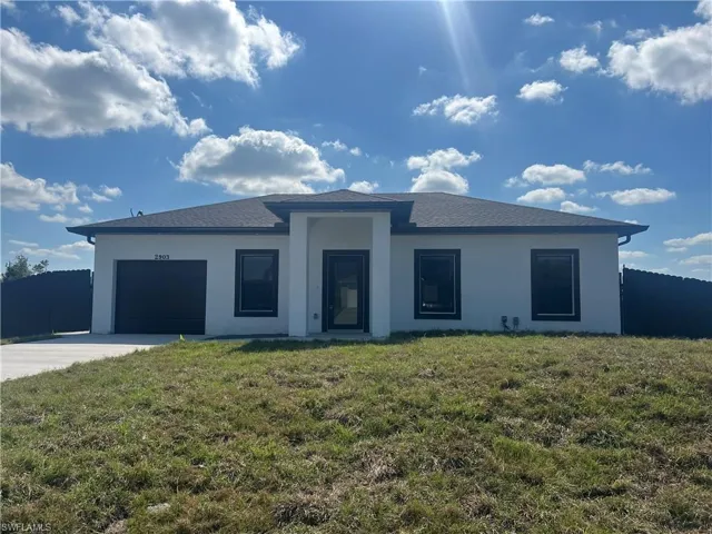 View of front facade with driveway, an attached garage, and stucco siding