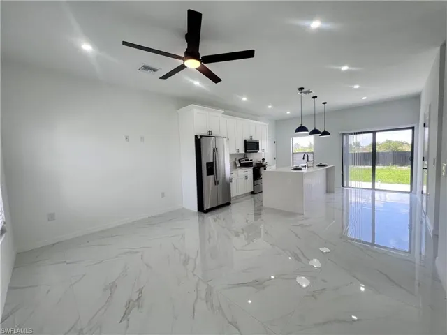Kitchen featuring appliances with stainless steel finishes, a sink, light marble finish flooring, baseboards, and recessed lighting