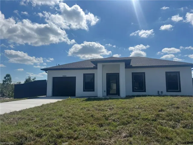 Prairie-style home featuring concrete driveway, an attached garage, stucco siding, and a front yard