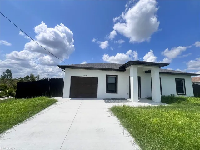 Prairie-style house with stucco siding, an attached garage, and driveway