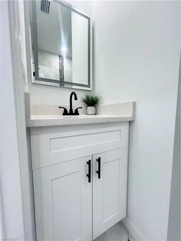 Bathroom featuring vanity, marble look tiles, and baseboards