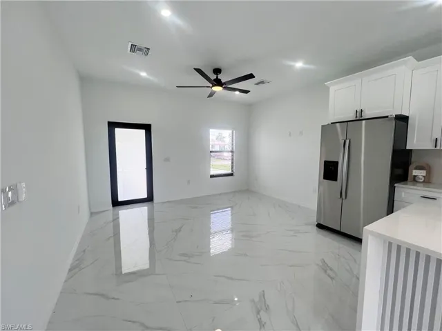 Kitchen with stainless steel refrigerator with ice dispenser, white cabinetry, a ceiling fan, baseboards, and recessed lighting