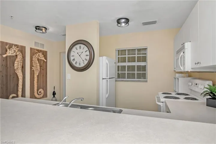 Kitchen with white cabinets, white appliances, and sink