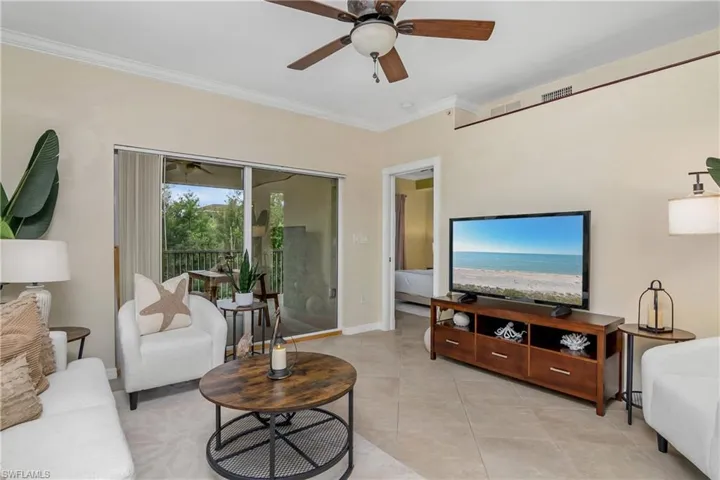 Living room featuring tile patterned floors, ornamental molding, and ceiling fan