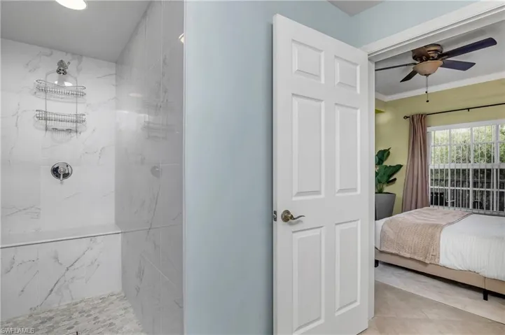 Bathroom featuring a tile shower, tile patterned flooring, ceiling fan, and ornamental molding