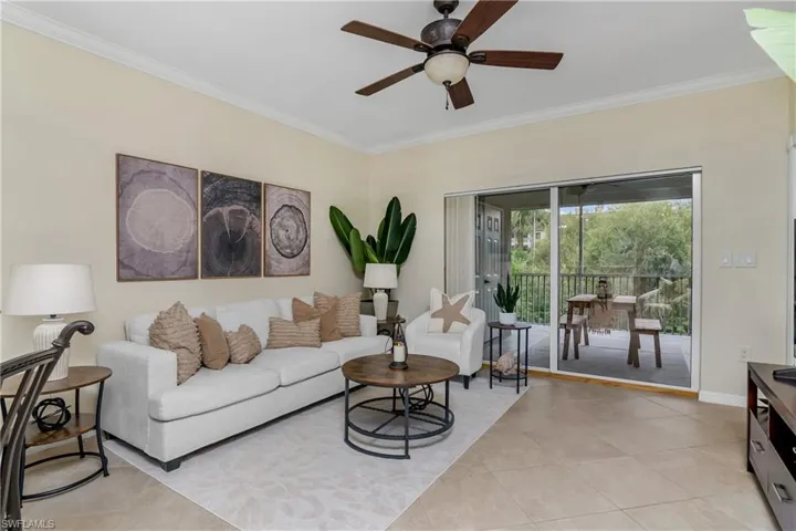 Living room featuring ceiling fan, ornamental molding, and light tile patterned floors