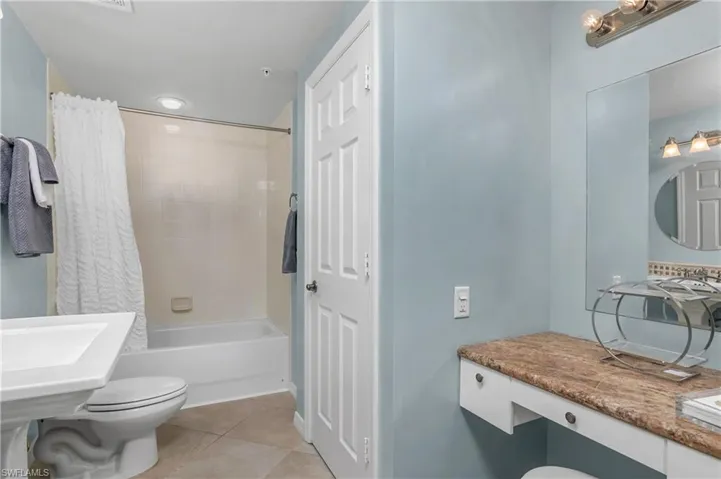 Bathroom featuring tile patterned floors, shower / tub combo, and toilet