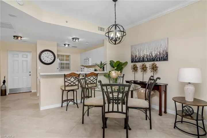 Dining space with ornamental molding, a notable chandelier, and light tile patterned floors