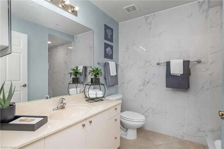 Bathroom with tile patterned flooring, tile walls, toilet, and vanity