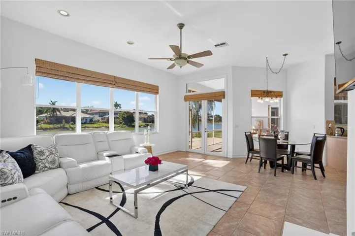 Living room with a water view, light tile patterned floors, ceiling fan, and a chandelier