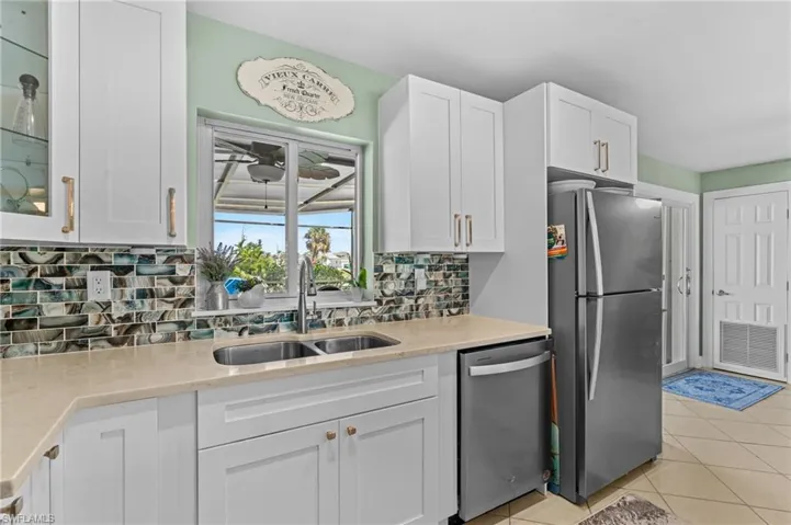 Kitchen with stainless steel appliances, a sink, visible vents, white cabinetry, and backsplash