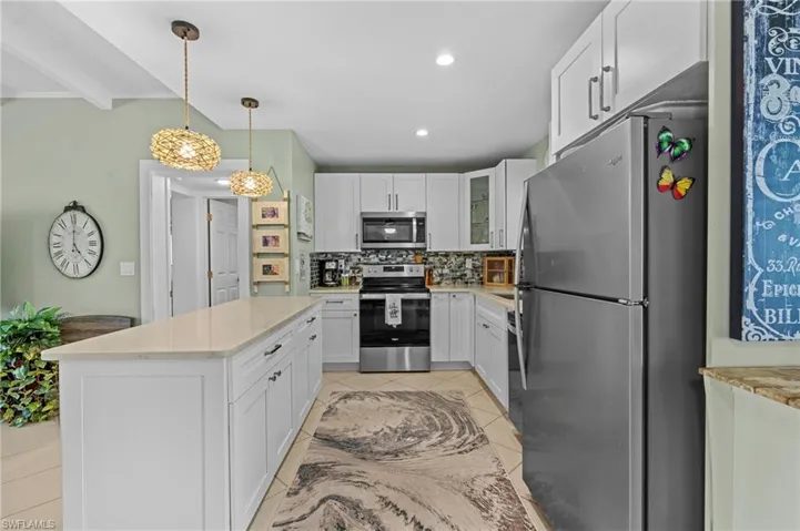 Kitchen with white cabinets, light tile patterned floors, appliances with stainless steel finishes, and decorative backsplash