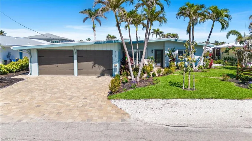 View of front of property featuring a front lawn, decorative driveway, and an attached garage virtually enhanced image