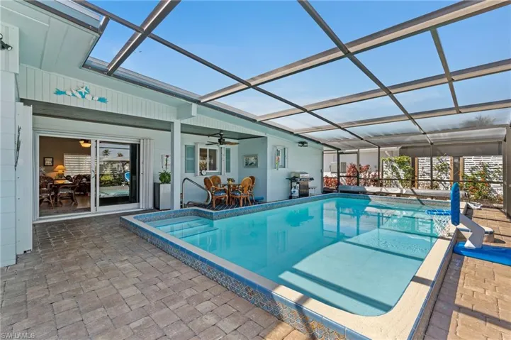 Pool with a lanai, a patio area, a grill, and a ceiling fan virtually enhanced image
