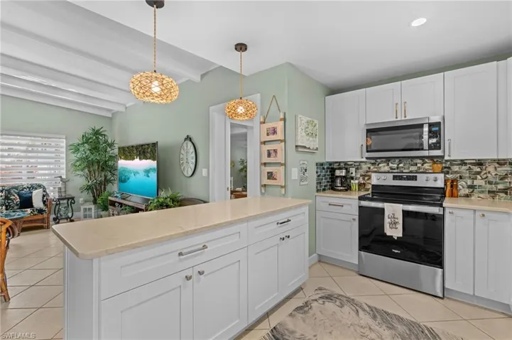 Kitchen with backsplash, stainless steel appliances, light countertops, and light tile patterned flooring