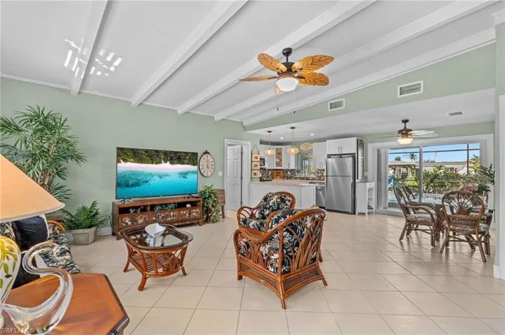 Living room featuring visible vents, vaulted ceiling with beams, and light tile patterned flooring