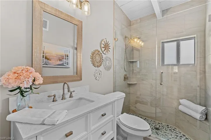 Full bath featuring visible vents, toilet, a shower stall, vanity, and beamed ceiling