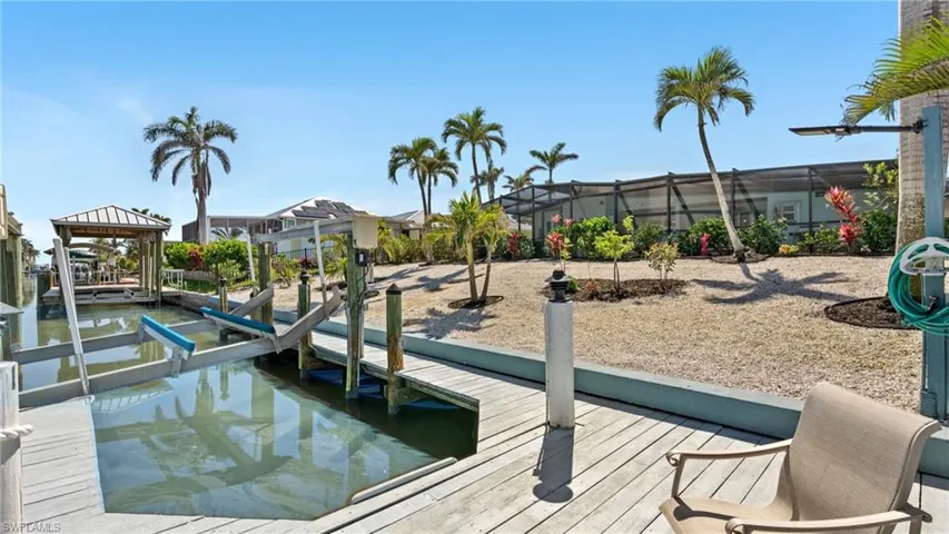 Dock area featuring boat lift and a lanai - VIRTUALLY ENHANCED