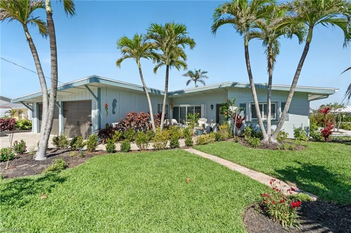 View of front of house featuring a front yard, driveway, and an attached garage - virtually enhanced image