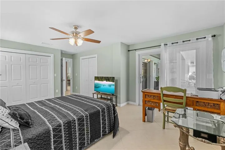 Bedroom featuring a ceiling fan, baseboards, two closets, and light tile patterned flooring