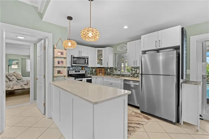 Kitchen featuring light tile patterned floors, appliances with stainless steel finishes, a sink, and white cabinetry