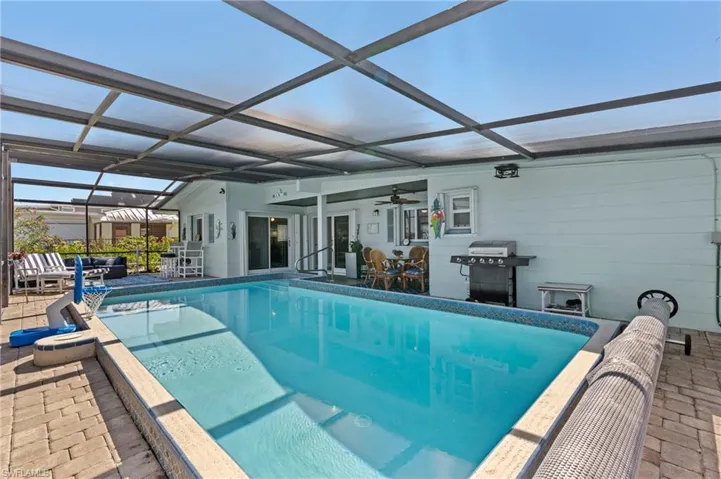 Outdoor pool with outdoor dining space, glass enclosure, a patio area, and area for grilling virtually enhanced image