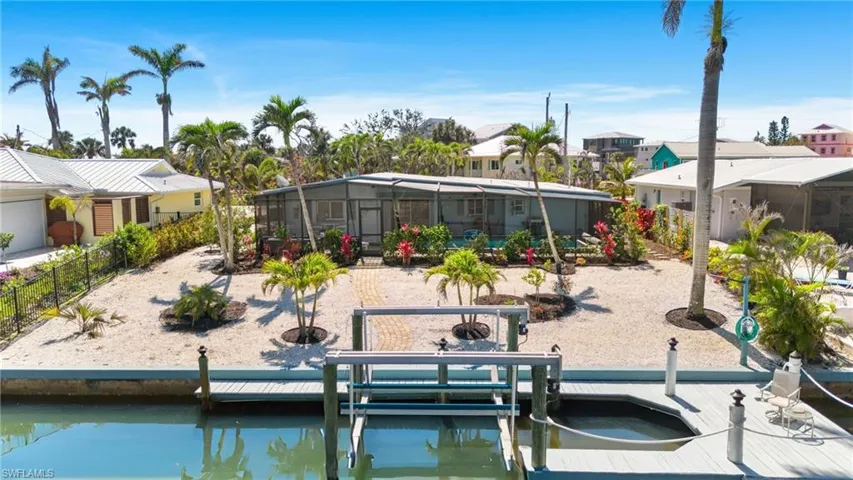 View of dock featuring a lanai, a water view, boat lift, and fence - VIRTUALLY ENHANCED