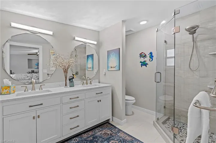 Bathroom featuring a stall shower, a sink, and baseboards