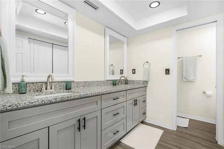 Dual vanity with light gray shaker-style cabinetry and granite-finish countertops.