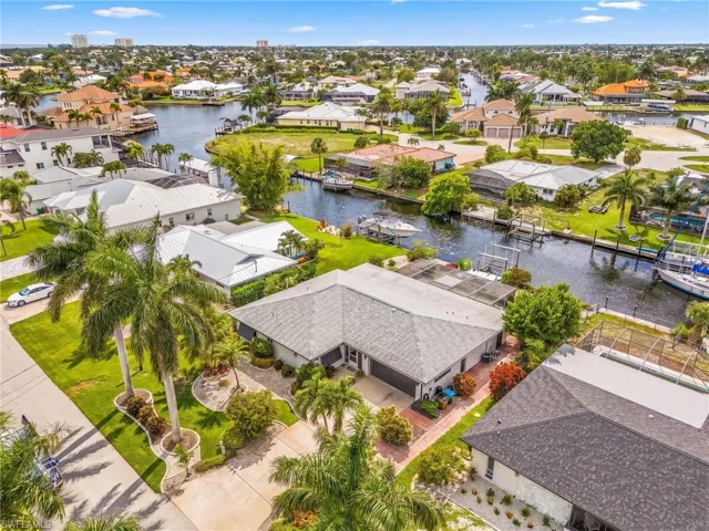 Expansive waterfront property featuring a paved driveway, mature palm trees, and a landscaped front yard