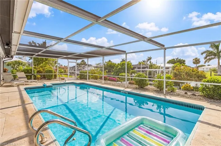 Screened outdoor heated swimming pool with light blue water and stainless steel handrails