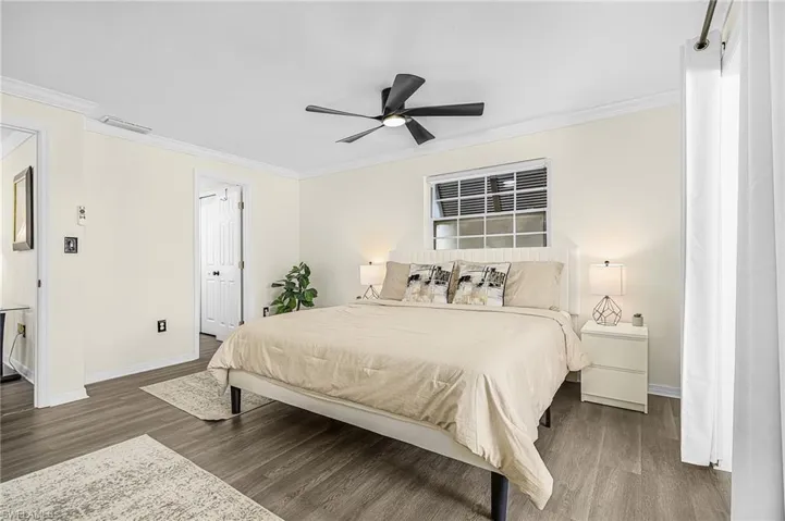 Spacious interior featuring wood-finish flooring, a ceiling fan, and crown molding.