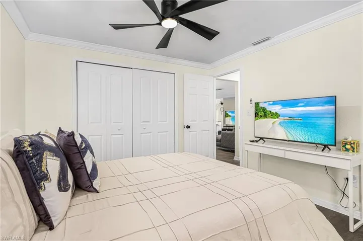 Bedroom space featuring crown molding, a ceiling fan with integrated lighting, and bi-fold closet doors