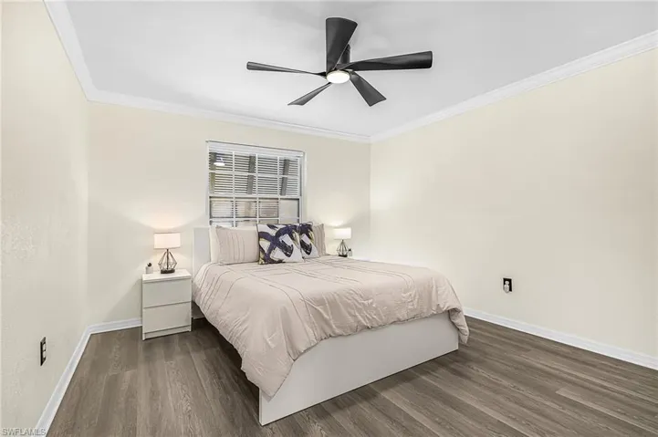 Spacious room featuring wood-finish flooring, light-colored walls, crown molding, and a contemporary ceiling fan