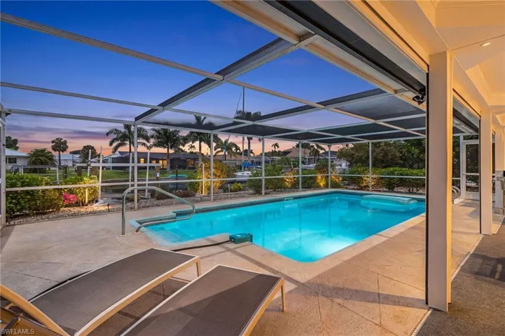 Screened swimming pool with a concrete paver deck and direct water access - no light in pool