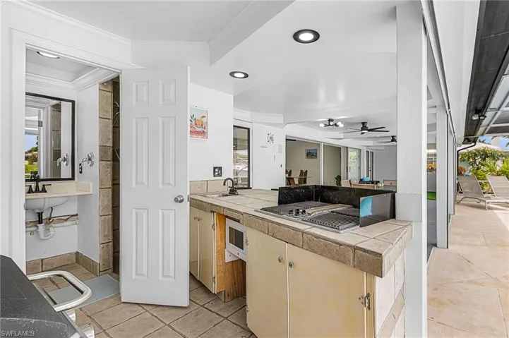 Outdoor kitchen with electric grill, microwave and sink. Also entry to 3rd full bath located off lanai.