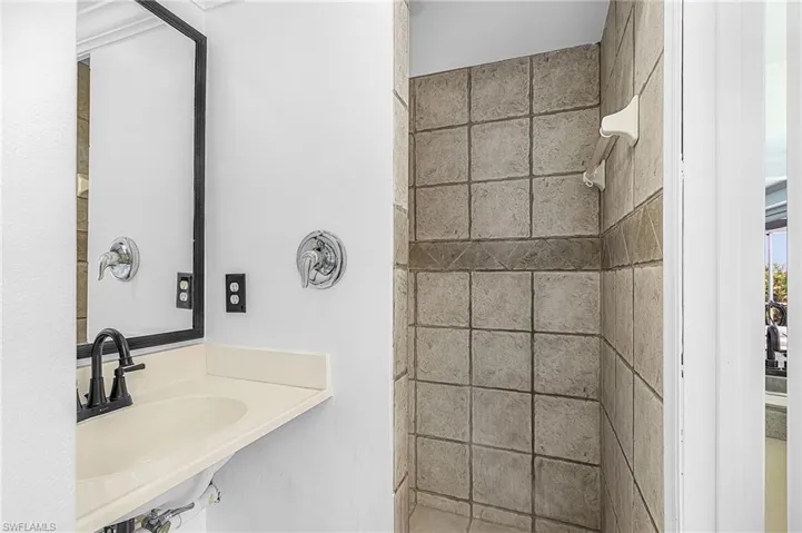 3rd full bath with an integrated sink, matte black faucet, and a framed mirror. Located off lanai