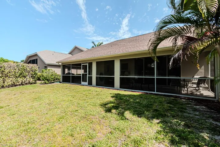 Rear view of house with a lawn and a screened lanai