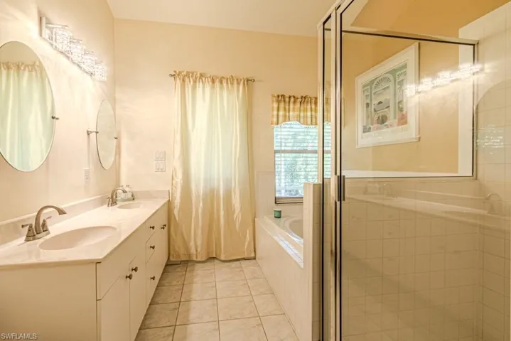 Bathroom featuring tile patterned flooring, vanity, and separate shower and tub
