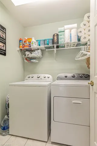 Clothes washing area with separate washer and dryer and light tile patterned floors