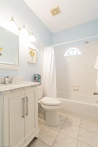 Full bathroom featuring tile patterned flooring, vanity, toilet, and shower / bathtub combination with curtain