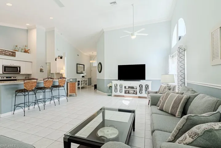 Tiled living room with a towering ceiling, ceiling fan, and crown molding