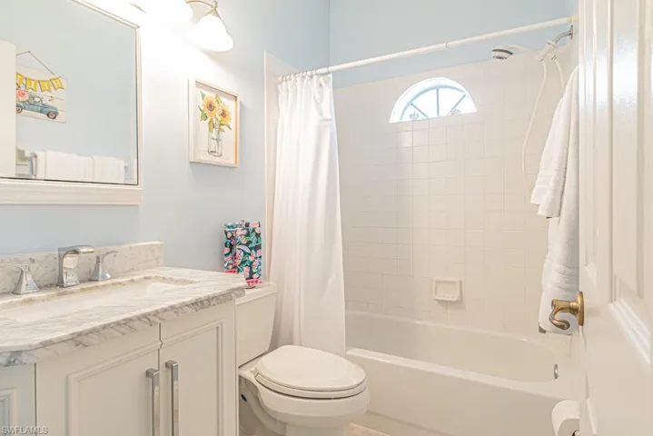 Full bathroom featuring vanity, toilet, and shower / bathtub combination with curtain