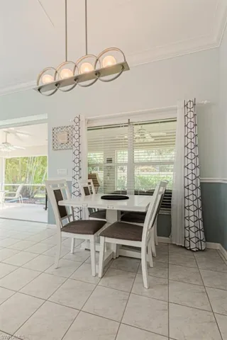 Tiled dining space with ceiling fan, a healthy amount of sunlight, and crown molding