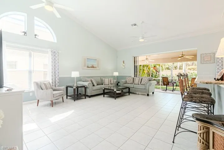 Living room featuring high vaulted ceiling, a healthy amount of sunlight, and light tile patterned flooring