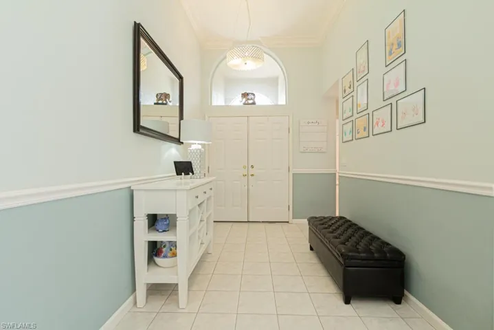 Foyer featuring light tile patterned flooring and crown molding
