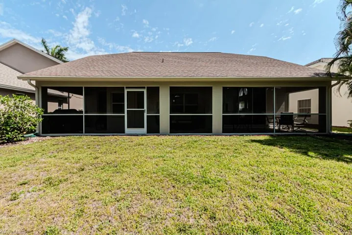 Rear view of house with a screened lanai and a yard