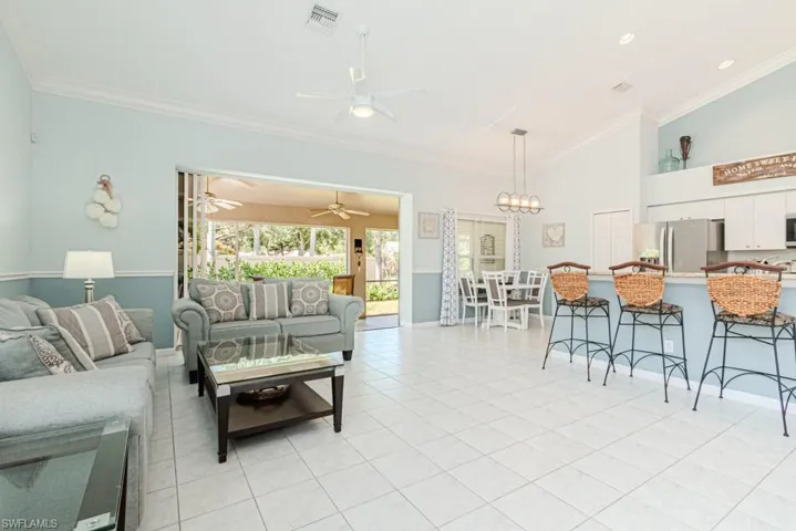 Tiled living room with an inviting chandelier, vaulted ceiling, and ornamental molding