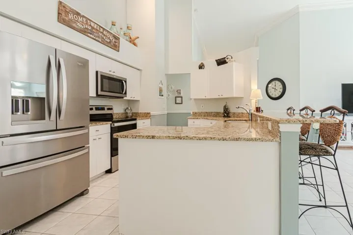Kitchen featuring white cabinets, high vaulted ceiling, kitchen peninsula, and appliances with stainless steel finishes