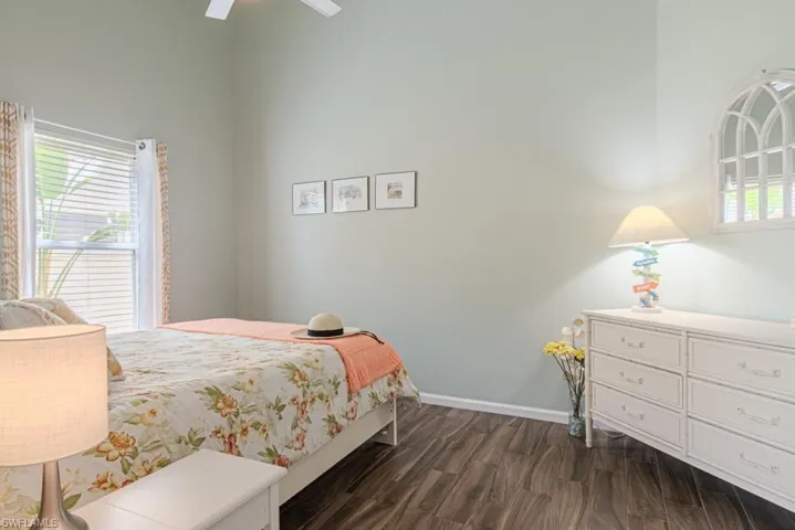 Bedroom with ceiling fan, a towering ceiling, and dark hardwood / wood-style floors